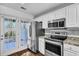 Bright kitchen with granite counters, white cabinets, stainless appliances, and patio access at 804 Buckthorn Cir, Summerville, SC 29483