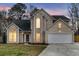 Beautiful two-story home with a two-car garage, arched windows, and dusk lighting at 113 Hartley Hall Ct, Summerville, SC 29485