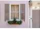 Close-up of a window box and shutters on a pink house with a gray front door and the number 12 at 12 Percy St, Charleston, SC 29403