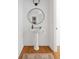Charming powder room featuring a pedestal sink, round mirror, modern lighting, and stylish decor on hardwood floors at 184 Scott St, Daniel Island, SC 29492
