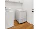 Bright laundry room boasts hardwood floors and modern white washer and dryer units, with overhead cabinets for storage at 184 Scott St, Daniel Island, SC 29492