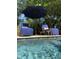 Relaxing poolside seating area with blue lounge chairs, umbrella, and beautiful water at 2664 Magnolia Woods Dr, Mount Pleasant, SC 29464