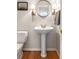 Small but stylish powder room with a pedestal sink, decorative sconces, and hardwood flooring at 2664 Magnolia Woods Dr, Mount Pleasant, SC 29464