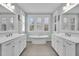 Elegant bathroom featuring dual sinks, and a standalone soaking tub under a window at 2876 Rivertowne Pkwy, Mount Pleasant, SC 29466