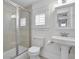 Clean bathroom featuring a glass-enclosed shower, toilet, pedestal sink, and window with shutters at 2876 Rivertowne Pkwy, Mount Pleasant, SC 29466