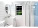 Bright bathroom with a shower, white vanity, framed round mirror, and a window providing natural light at 5 25Th Ave, Isle of Palms, SC 29451