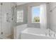 Bright bathroom featuring a bathtub, marble tile and glass shower at 506 Cecilia Cove Dr, Charleston, SC 29412