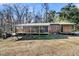This home features an extensive porch, trees in the background, and a well-manicured lawn at 5219 Maybank Hwy, Wadmalaw Island, SC 29487