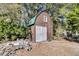 Exterior view of brown storage outbuilding with white door in wooded backyard at 5219 Maybank Hwy, Wadmalaw Island, SC 29487