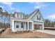 Charming light blue home featuring an attached two-car garage, a covered porch, and a gabled roof at 429 Grove End Rd, Moncks Corner, SC 29461