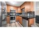 Well-lit kitchen featuring stainless steel appliances, wooden cabinets, black countertops, and modern backsplash at 7930 Timbercreek Ln # C, North Charleston, SC 29418
