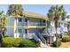Charming two-story condo with wood siding, and a beautiful porch, framed by lush greenery and swaying palm trees at 8 Lagoon Villas, Isle of Palms, SC 29451