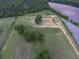 A scenic aerial view showcases a pond surrounded by mature trees and expansive green fields edged by woods at 1758 Mendel Rivers Rd, Saint Stephen, SC 29479