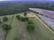 This aerial shot showcases a vast property featuring a mix of farmland, trees, outbuildings, and gardens at 1758 Mendel Rivers Rd, Saint Stephen, SC 29479
