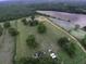 An aerial view shows a spacious lot with mature trees, outbuildings, and an excavated pond at 1758 Mendel Rivers Rd, Saint Stephen, SC 29479