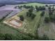 Expansive aerial view highlighting a pond with surrounding green space, framed by lush trees and neighboring farmland at 1758 Mendel Rivers Rd, Saint Stephen, SC 29479