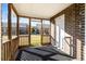 View of a cozy screened porch with brick accent wall, outdoor rug, and sun-drenched view of neighborhood at 1860 Mepkin Rd # H1, Charleston, SC 29407