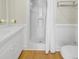Bathroom with wooden floors featuring white cabinets, shower, and toilet at 2710 Laroche St, Edisto Beach, SC 29438