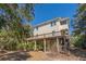 Exterior angle of two-story home showing a wraparound porch and mature trees around property at 2710 Laroche St, Edisto Beach, SC 29438