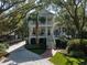 Beautiful home with a manicured front lawn and a two-story porch, framed by mature trees providing shade and charm at 2863 Jasper Blvd, Sullivans Island, SC 29482