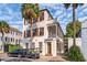 Stately multi-story home showcasing a beautiful facade, private golf cart, mature palm trees, and a blue sky backdrop at 38 State St # 2, Charleston, SC 29401