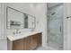 Modern bathroom with dual sinks, wood cabinetry, a large mirror, and a glass-enclosed shower at 4057 E Amy Ln, Johns Island, SC 29455