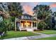 Charming two-story home with a welcoming front porch, lush lawn, and beautiful palm trees at sunset at 4057 E Amy Ln, Johns Island, SC 29455