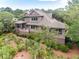 Back exterior view features a screened porch and verdant landscaping, creating a private and serene retreat at 57 Goldenrod Ct, Kiawah Island, SC 29455