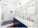 Modern bathroom featuring double sinks with marble countertops, navy blue cabinets and a glass-enclosed shower at 1 Percy St, Charleston, SC 29403
