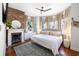 Bright bedroom featuring a fireplace, brick accent wall, and a large window bay that fills the room with natural light at 1 Percy St, Charleston, SC 29403