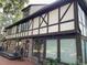 Rear exterior view of Tudor-style home, showcasing brickwork, windows, and deck at 104 Legend Oaks Way, Summerville, SC 29485