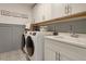 Well-organized laundry room with modern washer and dryer, sink, and ample storage cabinets at 110 Crosscut Ln, Summerville, SC 29486