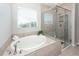 Bathroom featuring a standalone tub, a tiled shower stall with glass door, and a window at 123 Lakelyn Rd, Moncks Corner, SC 29461