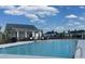 A large in-ground pool sits next to a modern building with white columns, and a dark grey roof under a bright sky at 132 Grange Cir, Summerville, SC 29486