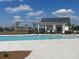 A bright blue community pool sits next to a modern clubhouse and black wrought iron fence, under a bright blue sky at 132 Grange Cir, Summerville, SC 29486
