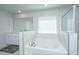 Bright bathroom featuring a soaking tub with marble tile surround and double sink vanity with a large mirror at 143 Oyster Tide Ave, Summerville, SC 29485
