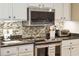 Modern kitchen with stainless steel microwave, stove, granite countertops, white cabinets, and a mosaic backsplash at 145 Pier View St # 316, Charleston, SC 29492