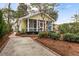 Inviting yellow home with a screened-in porch, complemented by manicured landscaping and a paved driveway at 221 Church St, Mount Pleasant, SC 29464