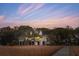 Charming home exterior featuring a wooden dock, marsh grasses, and mature trees at sunset at 232 Haddrell St, Mount Pleasant, SC 29464