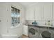 Convenient laundry room features modern washer and dryer, cabinets, and a sunlit window at 232 Haddrell St, Mount Pleasant, SC 29464