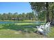 Scenic view of the waterfront backyard featuring white Adirondack chairs and mature trees at 4162 Ten Shillings Way, Hollywood, SC 29470