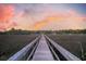 Picturesque boardwalk view showcasing a stunning sunset, framed by lush greenery, creating a serene and tranquil escape at 4385 Ten Shillings Way, Hollywood, SC 29470
