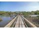 Scenic dock view leading to a covered boathouse, complete with an American flag and tranquil river scenery at 4385 Ten Shillings Way, Hollywood, SC 29470
