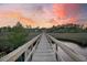 Picturesque wooden dock stretching over the water, leading to a home in a serene waterfront setting at sunset at 4385 Ten Shillings Way, Hollywood, SC 29470