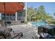 Relaxing patio area with a pool view, featuring comfortable seating, an umbrella, and a charming brick-detailed house at 4385 Ten Shillings Way, Hollywood, SC 29470