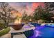 Twilight view of pool featuring fire bowls, gentle waterfall, vibrant lighting, creating a captivating and enchanting ambiance at 4385 Ten Shillings Way, Hollywood, SC 29470
