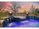 Inviting pool at dusk showcasing captivating fire bowls, serene waterfall features, and vibrant, colorful lighting at 4385 Ten Shillings Way, Hollywood, SC 29470
