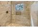 Elegant bathroom shower featuring travertine tile, glass door, and a window for natural light at 4385 Ten Shillings Way, Hollywood, SC 29470