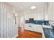 Open kitchen with hardwood floors, white cabinetry, blue tile countertops, and floral wallpaper at 6 Halsey St, Charleston, SC 29401