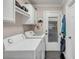 Bright laundry room featuring washer, dryer, white cabinets and shelving, and black tile flooring at 74 6Th Ave, Charleston, SC 29403